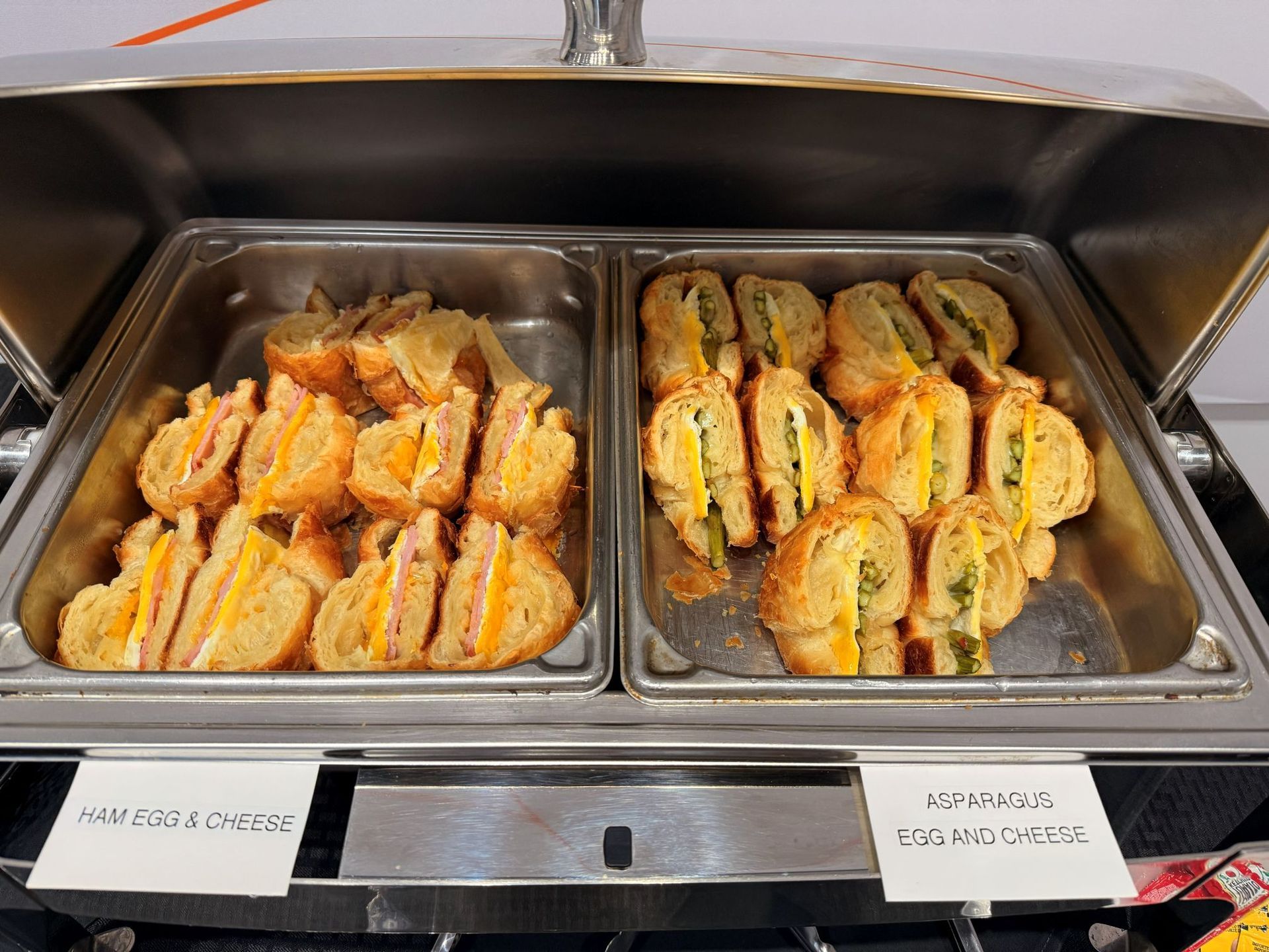 Two warming trays filled with sandwiches. Left tray: ham and cheese. Right tray: chicken sandwiches.