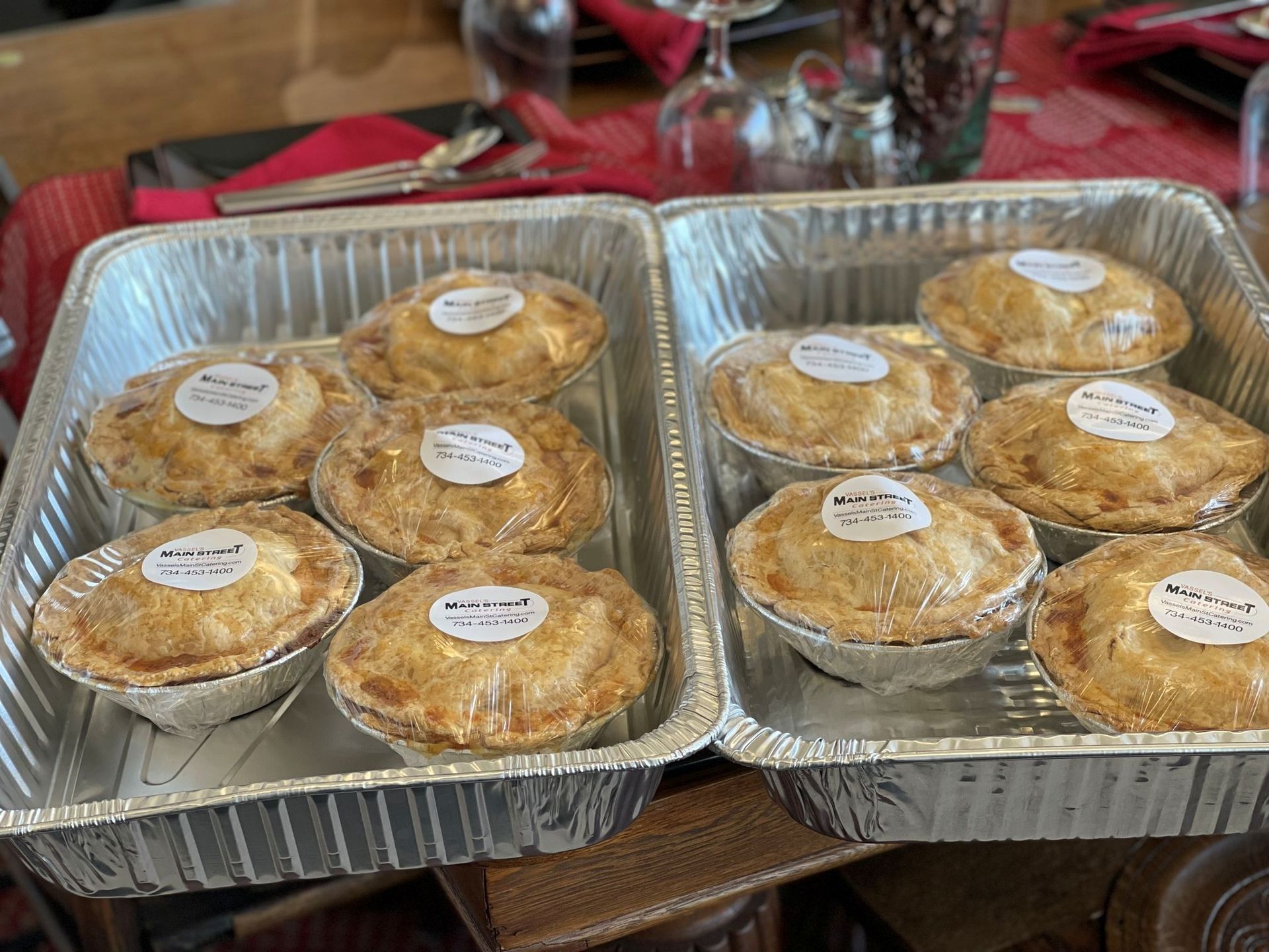 Two foil trays with individual pies, each wrapped, on a table.