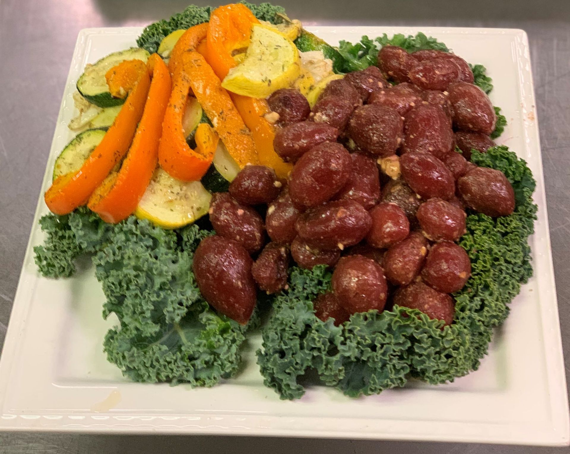 Plate with kale, roasted vegetables (carrots, squash, zucchini) and grapes.