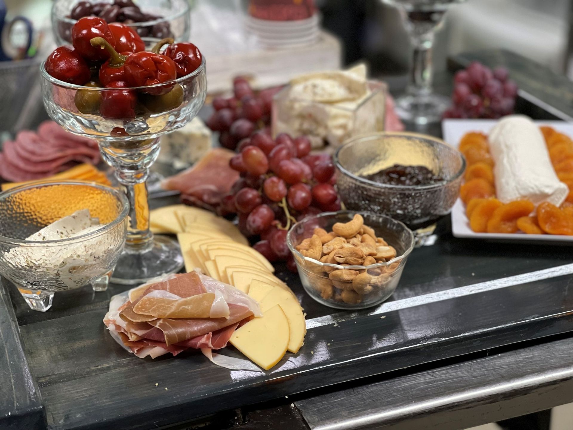 Charcuterie board: cheeses, grapes, cherries, nuts, meats, dried apricots, and jam.