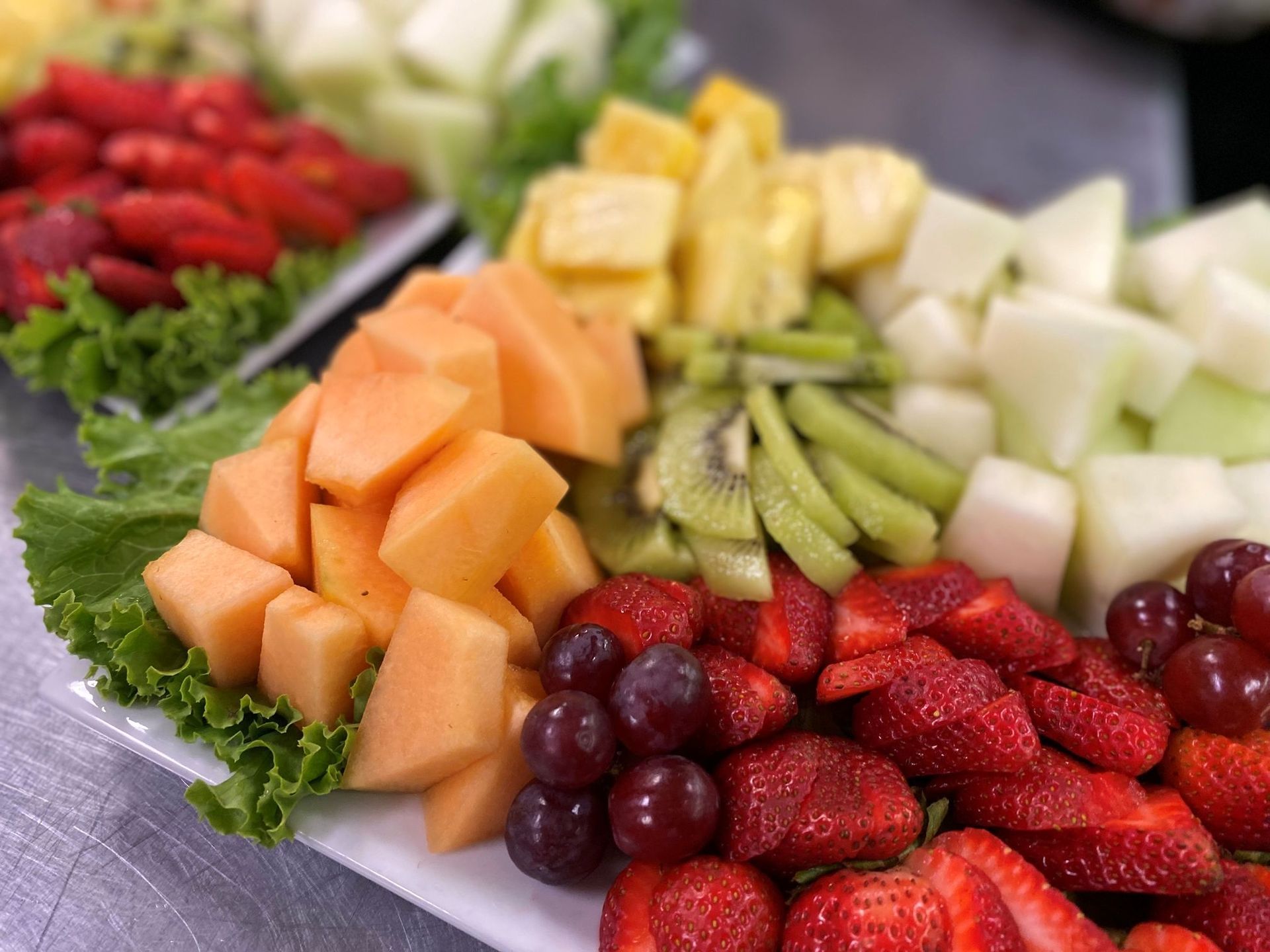 Fruit platter with cantaloupe, strawberries, grapes, kiwi, pineapple, and melon.