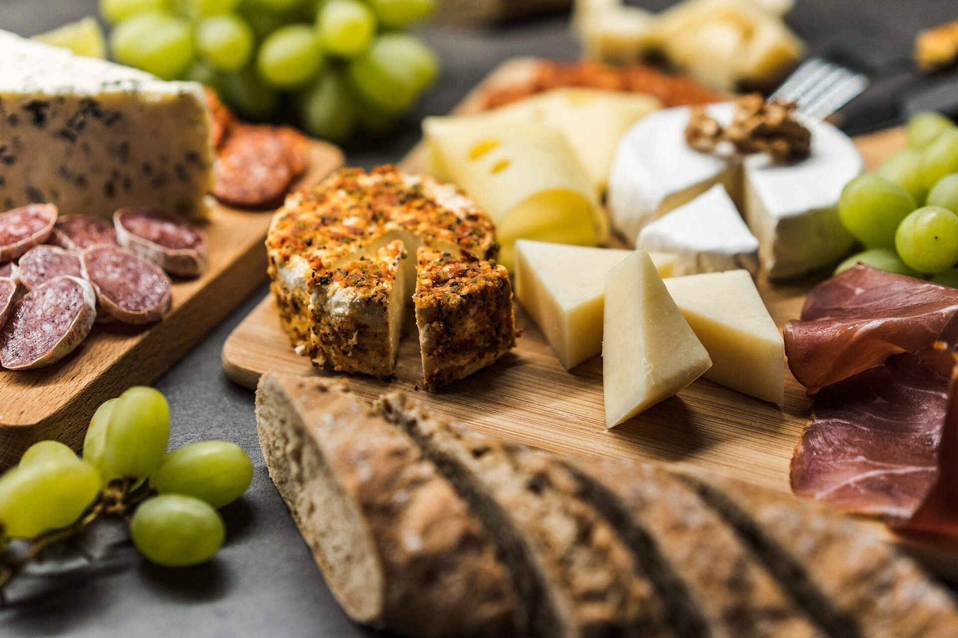 Cheese and meat board with grapes and bread.