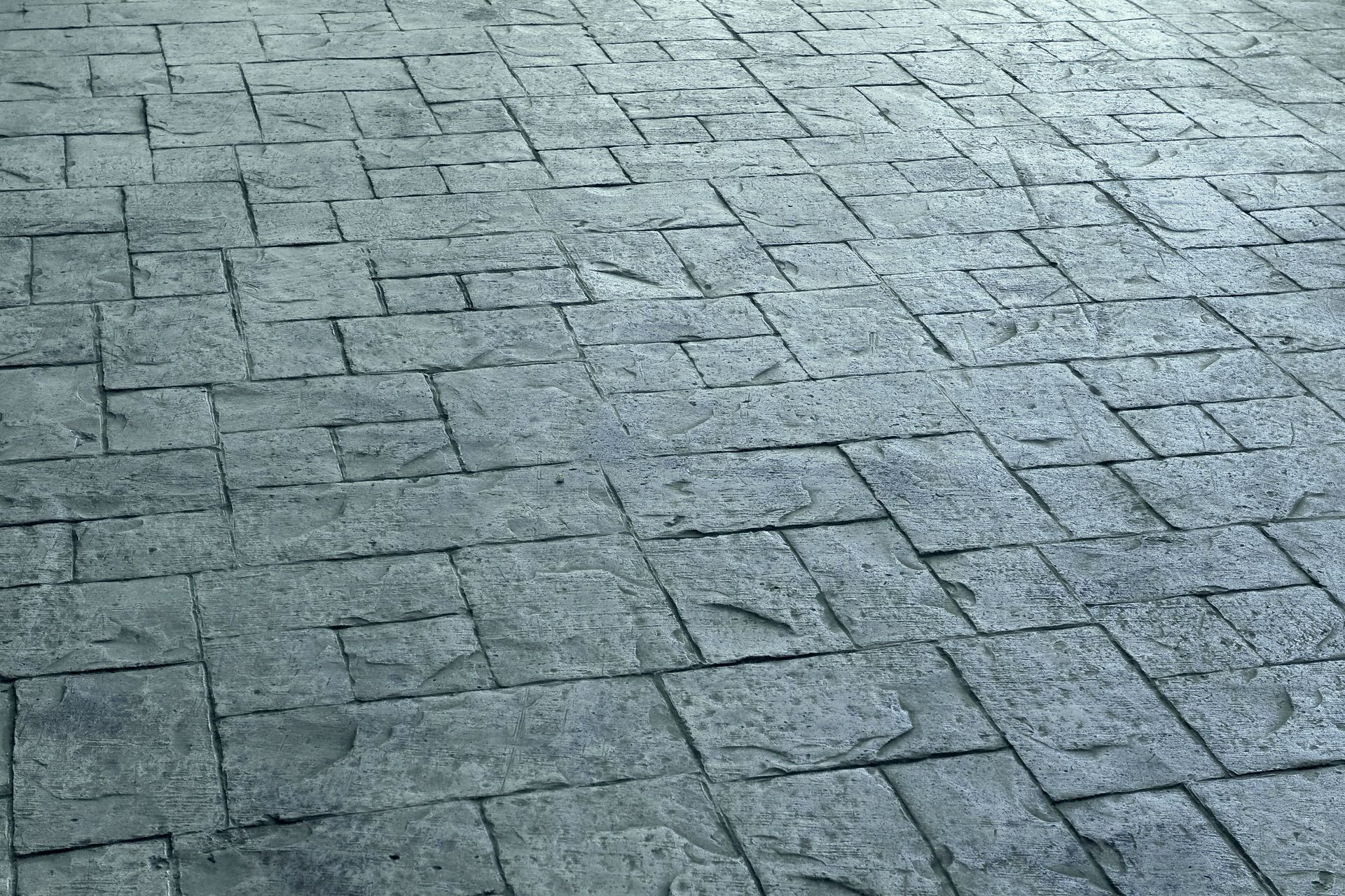 Gray, textured stamped concrete patio, resembling stone blocks.