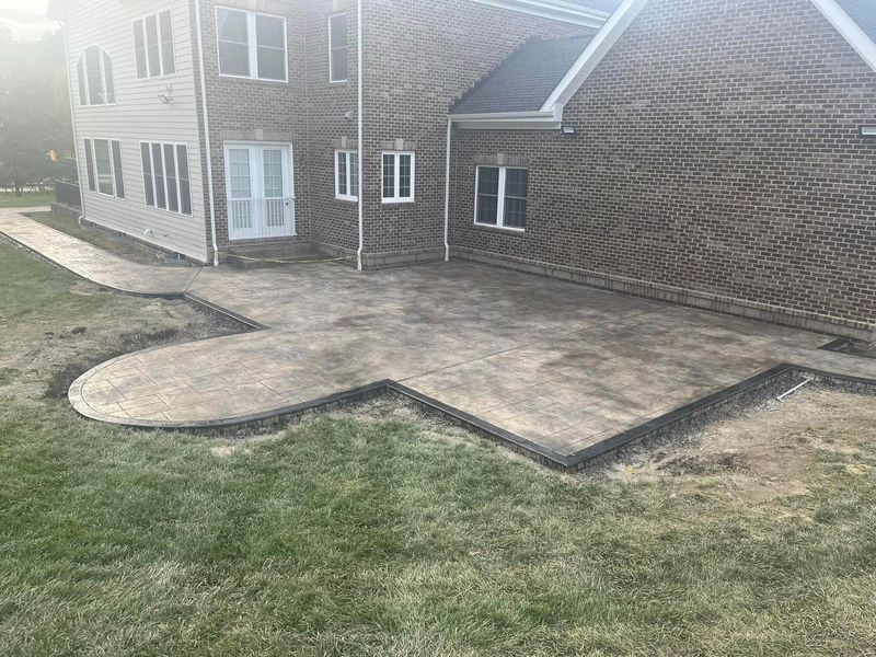Brick house with concrete patio and walkway on a grassy lawn.