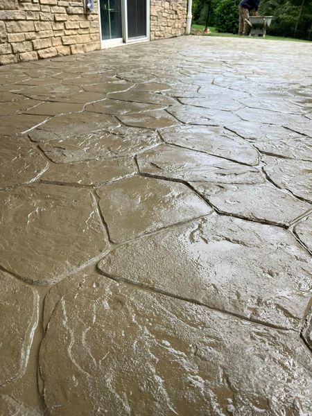 Stamped concrete patio with a stone pattern, light brown with wet-look sheen.