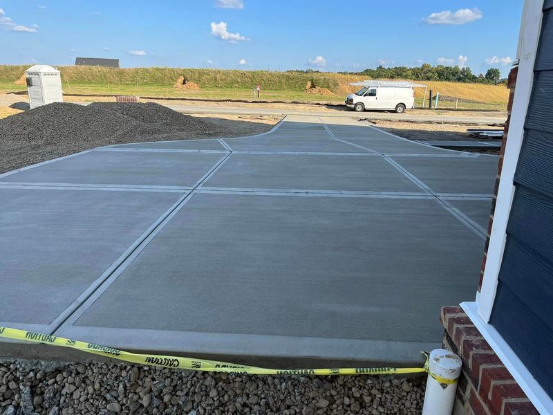 Newly poured concrete driveway with expansion joints; construction site with white van.
