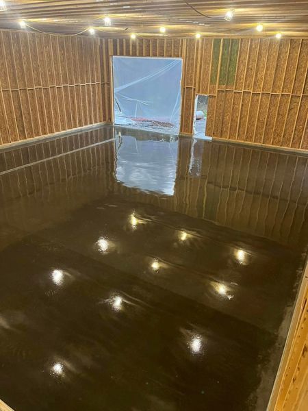 Empty room with a shiny, dark floor reflecting overhead lights. Wooden walls.