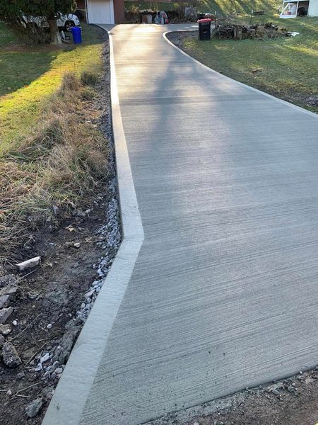 Newly poured concrete driveway with a gray surface and a concrete curb.