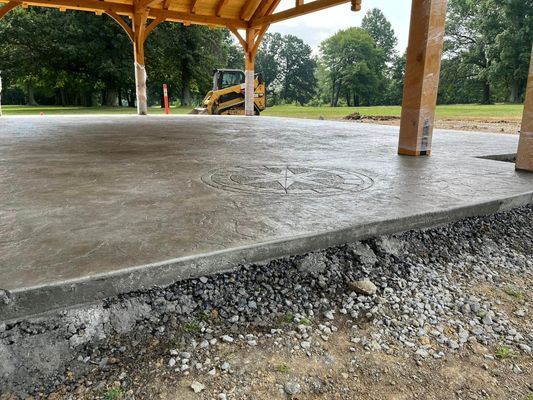 A freshly poured concrete pavilion floor with a Caterpillar bulldozer in the background.