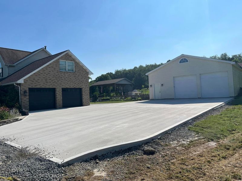 A concrete driveway connects a house with a garage, set on a sunny day.