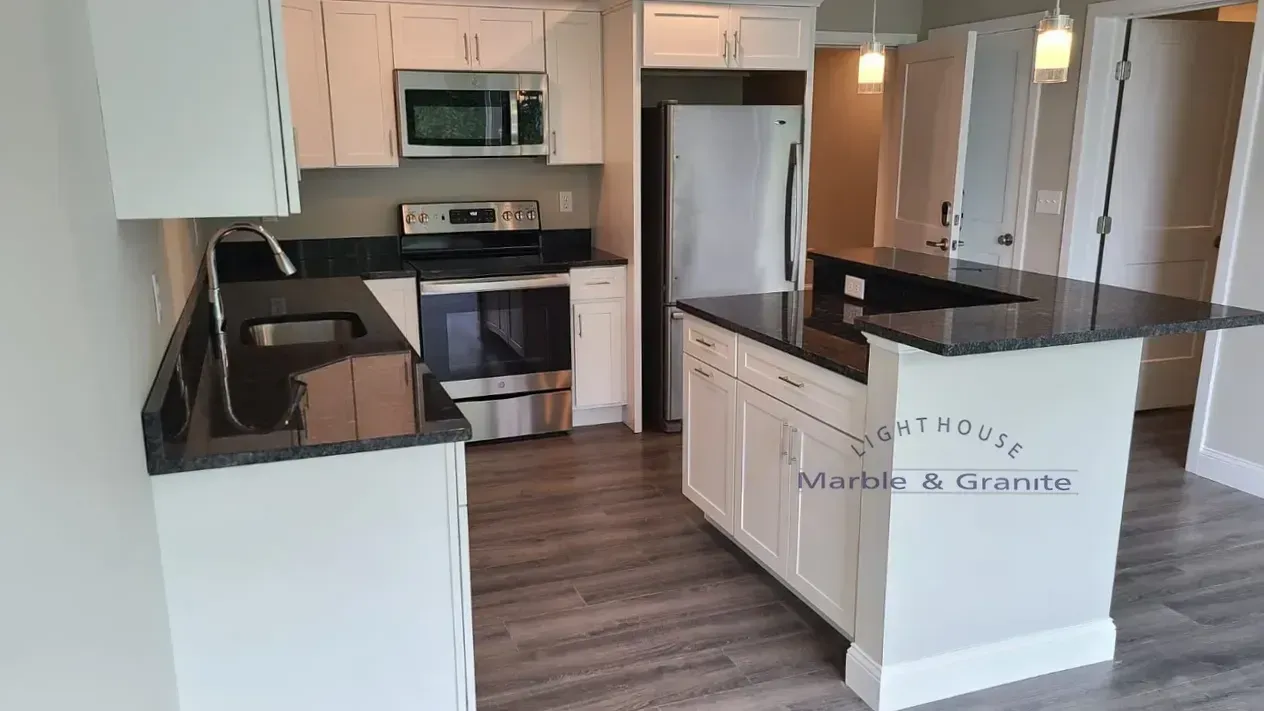 Kitchen with white cabinets, dark countertops, stainless steel appliances, and a gray floor.