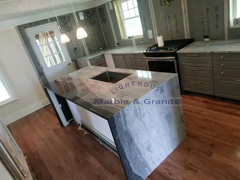 Kitchen with gray cabinets, granite island, and wood floors.