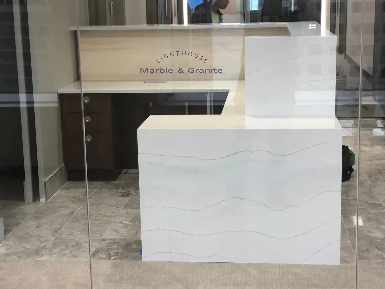 Reception desk with white quartz counter and wooden backdrop; 