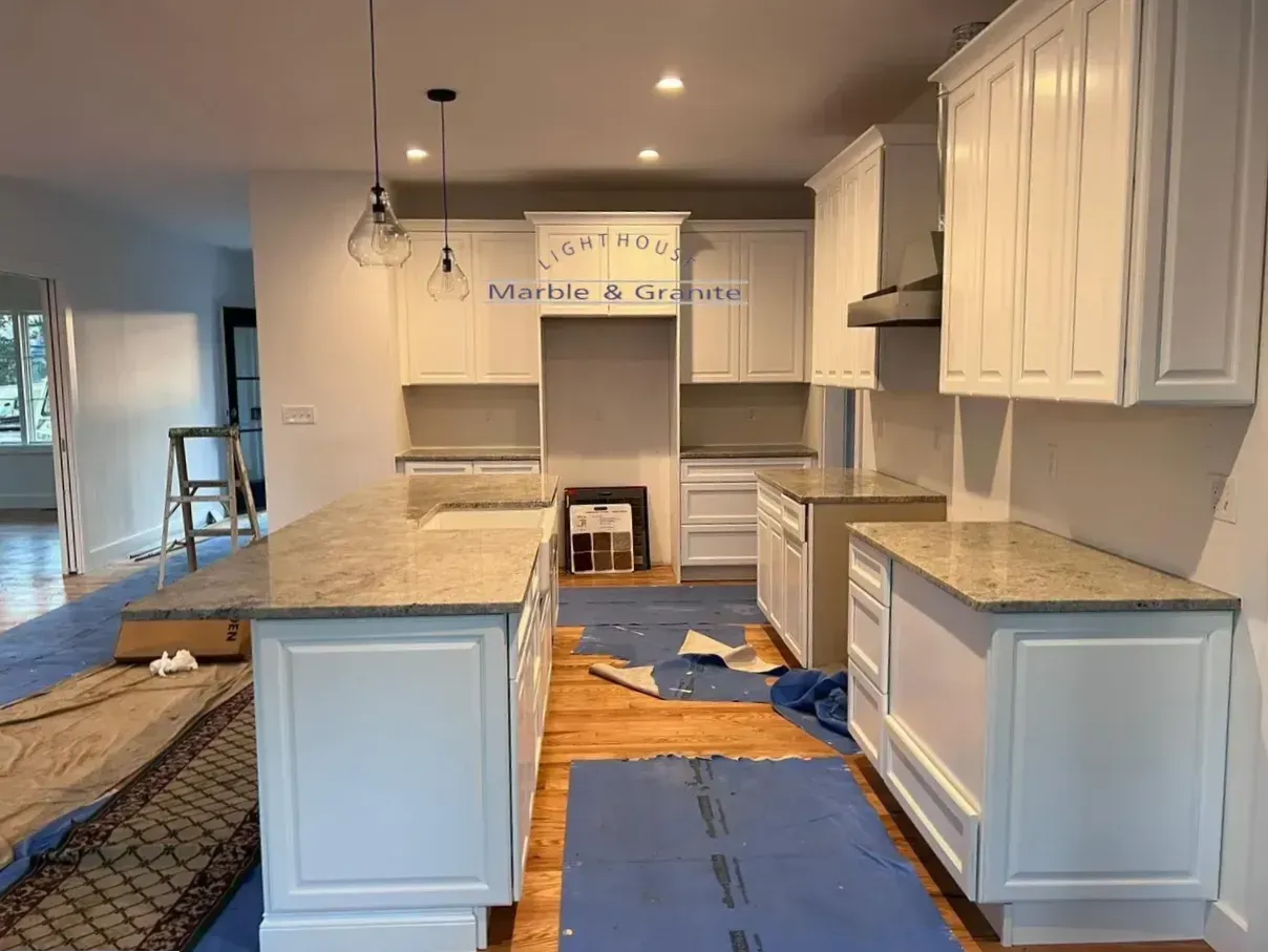 Newly renovated kitchen with white cabinets, granite countertops, and island. Construction in progress.