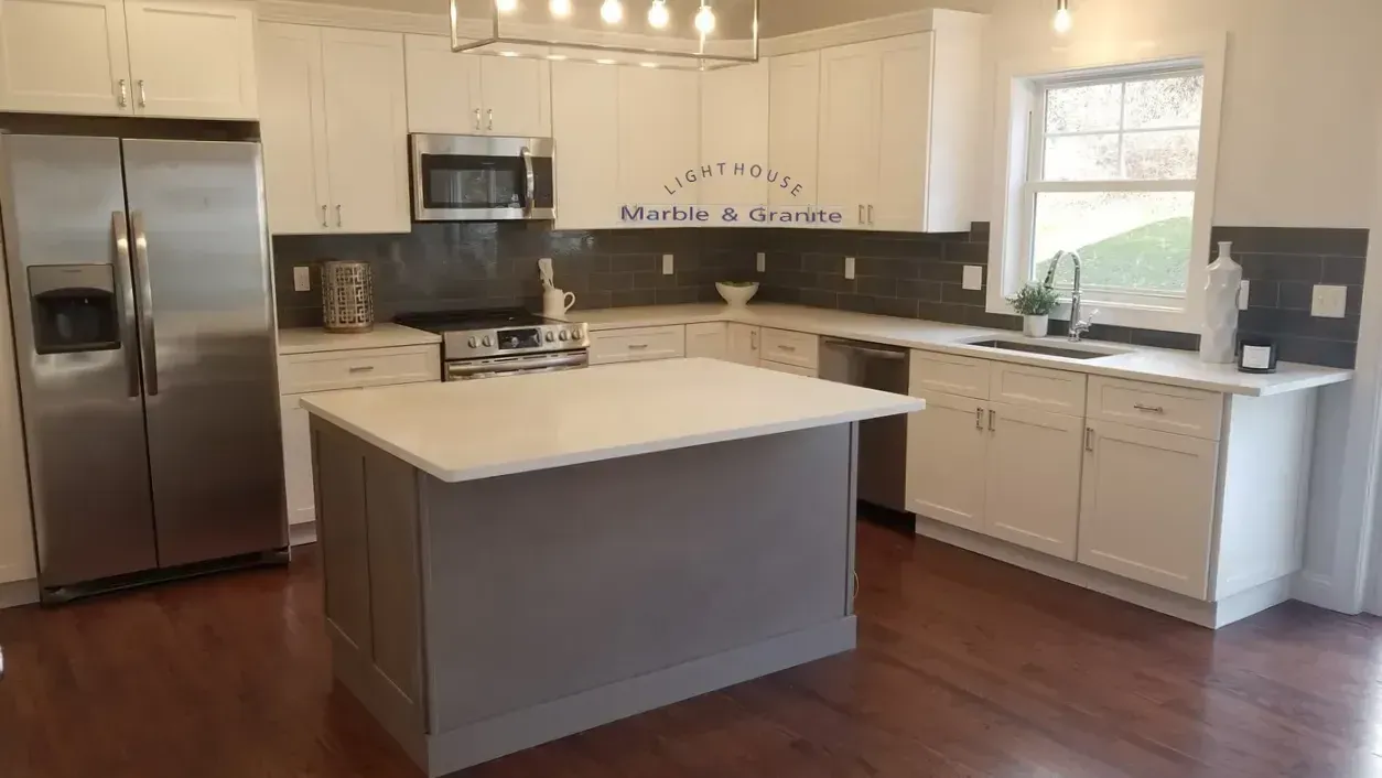 Modern kitchen with white cabinets, gray island, stainless steel appliances, and dark wood floors.