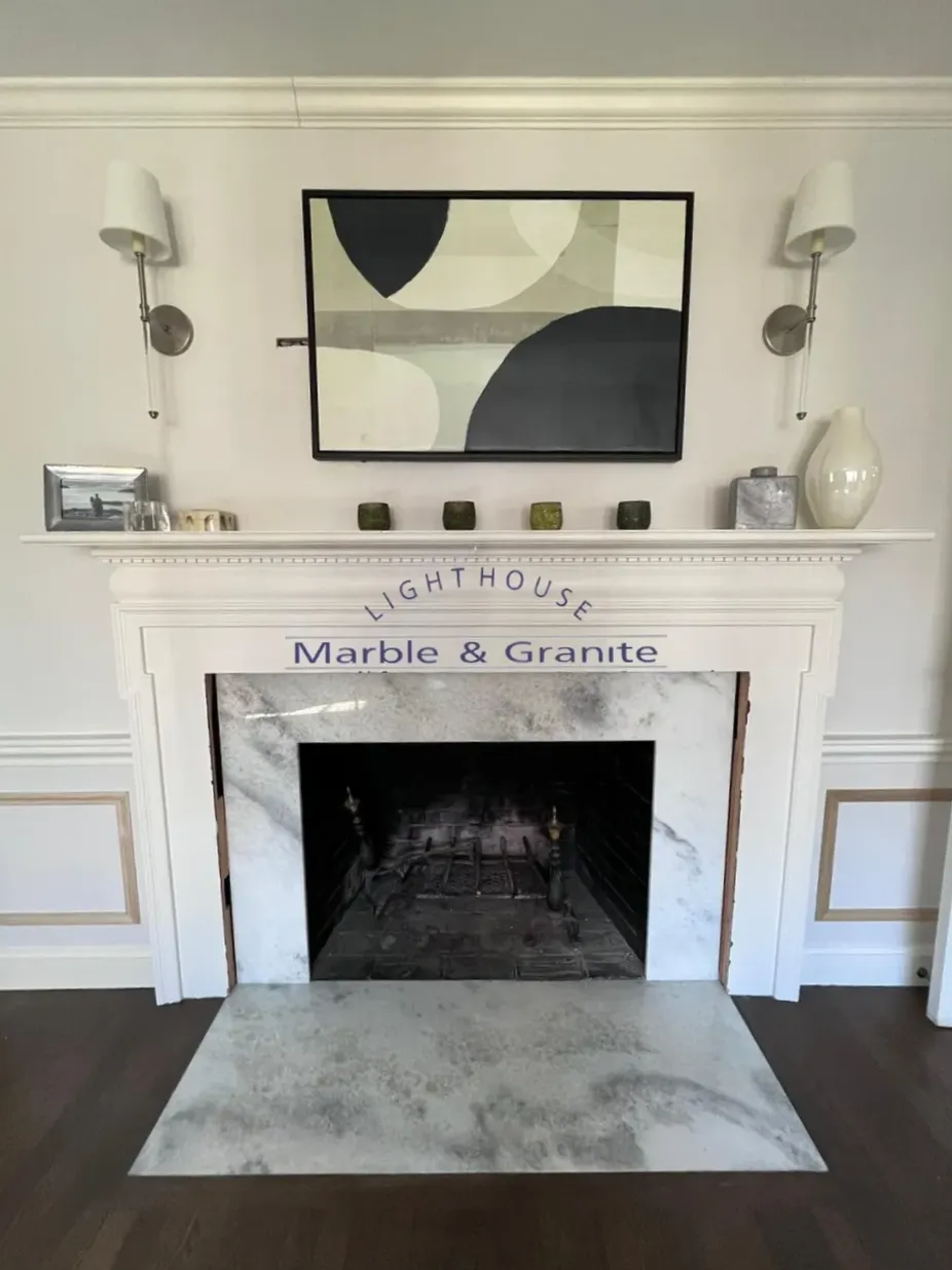 White marble fireplace with artwork and sconces.