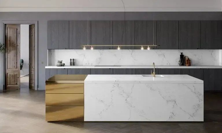 Modern kitchen with marble island and gold accents, gray cabinets, and open doorway.