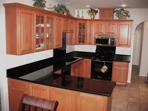 Wooden kitchen cabinets with black countertops, and a black oven.