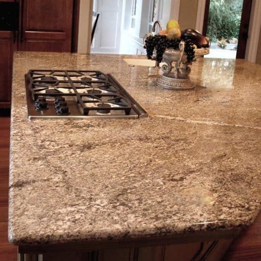 Granite kitchen island with a built-in gas stovetop and fruit arrangement.