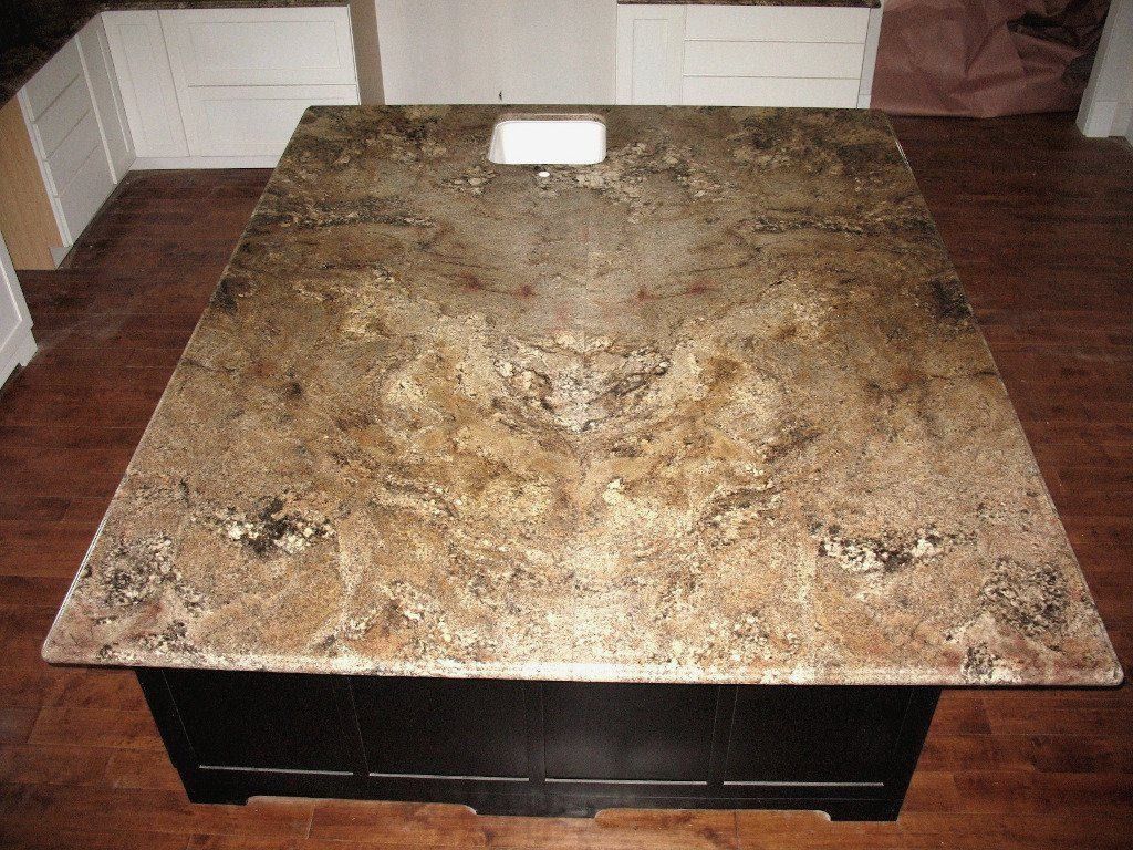 Kitchen island with granite countertop and dark cabinetry, containing a sink.