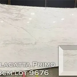 Large slab of white Lacatta Primo marble with grey veining, sample in the corner.