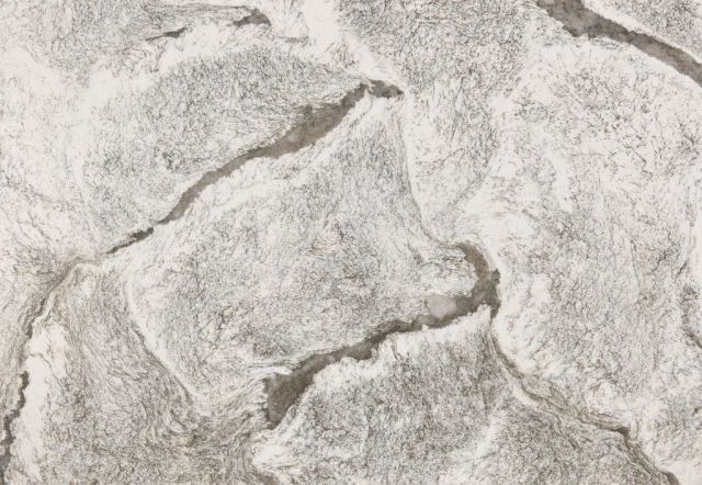 Close-up of a textured surface, primarily grey and white, resembling stone or rock formations with irregular cracks.
