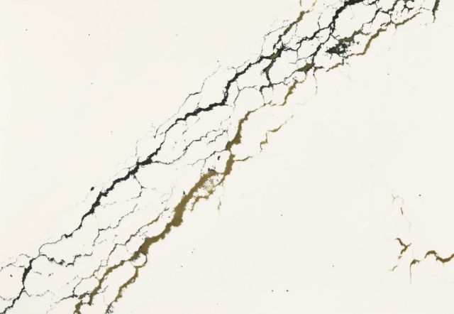 Cream-colored surface with dark, crack-like veining diagonally across it.