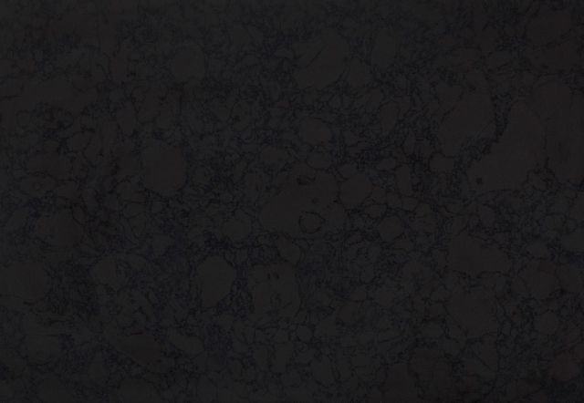 Dark, textured surface with faint, irregular patterns and subtle shading.