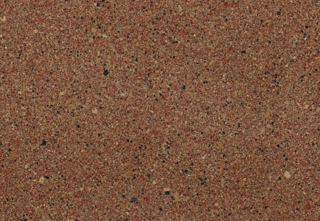 Reddish-brown concrete surface with small, dark-colored speckles.