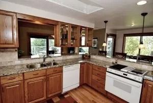 Kitchen with wood cabinets, granite countertops, white appliances, and a pass-through window.