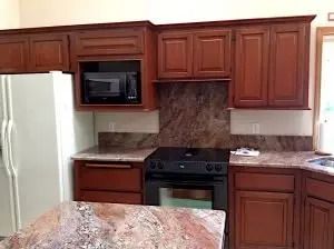 Kitchen with brown cabinets, granite countertops, microwave, and stove.
