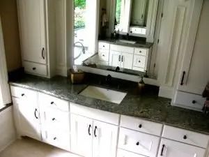 Bathroom with white cabinets, dark countertop, and large mirror.