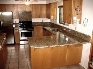 Kitchen with light wood cabinets, granite countertops, and stainless steel appliances.