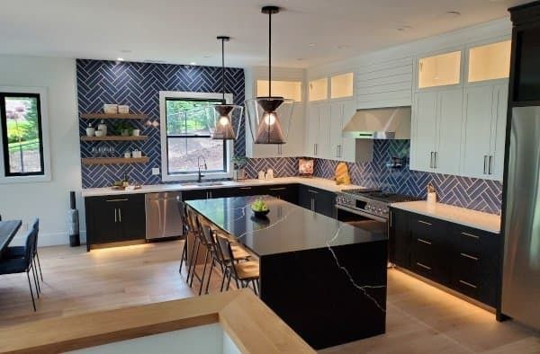 Modern kitchen with black and white cabinets, island, and blue backsplash.