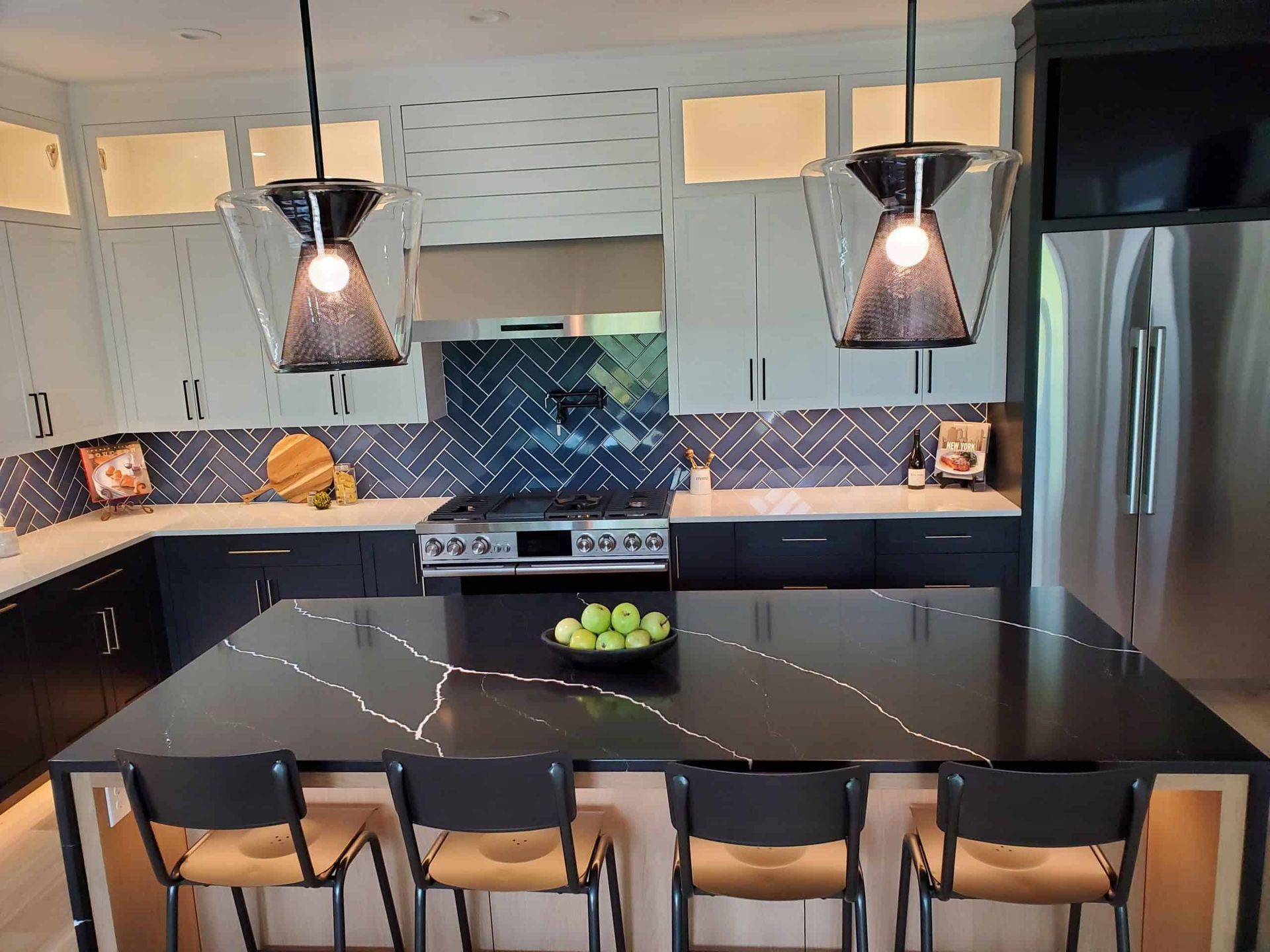 Modern kitchen with black and white cabinets, island with stools, pendant lights.