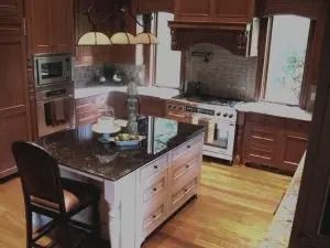 Kitchen with cherry cabinets, granite countertops, island with seating, and stainless steel appliances.