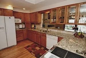 Oak kitchen with granite counters, a view-through window, and a refrigerator.