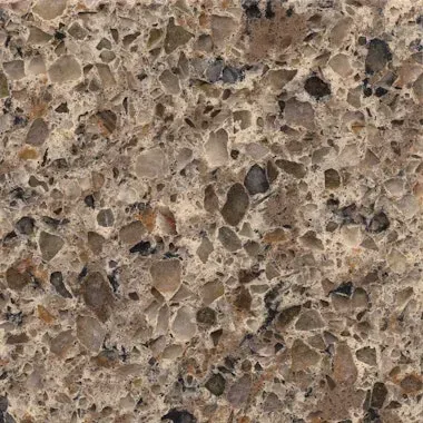 Close-up of brown quartz countertop with a speckled pattern of various colored aggregates.