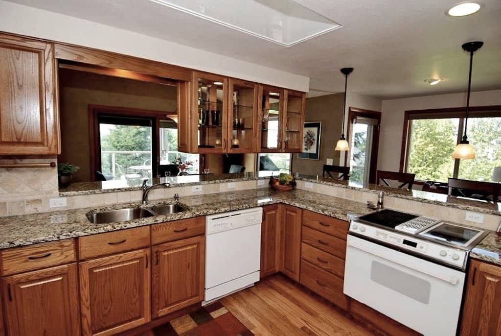 Kitchen with wooden cabinets, granite countertops, white appliances, and a view to the outdoors.