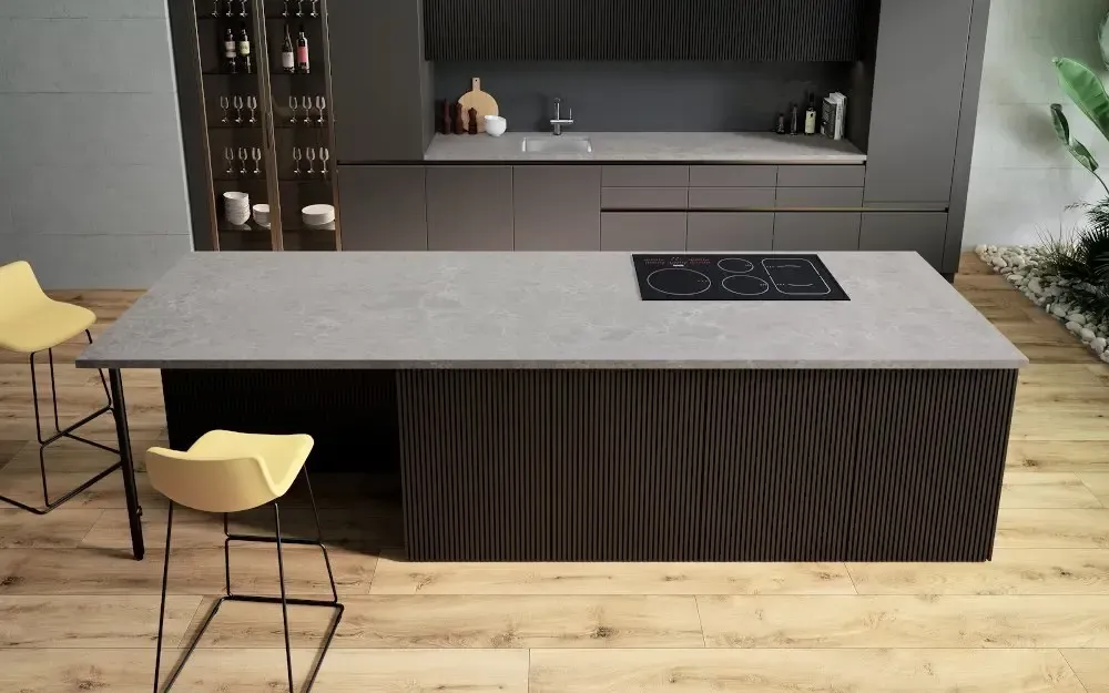 Modern kitchen with gray countertops, dark wood cabinets, island with stovetop, yellow stools.