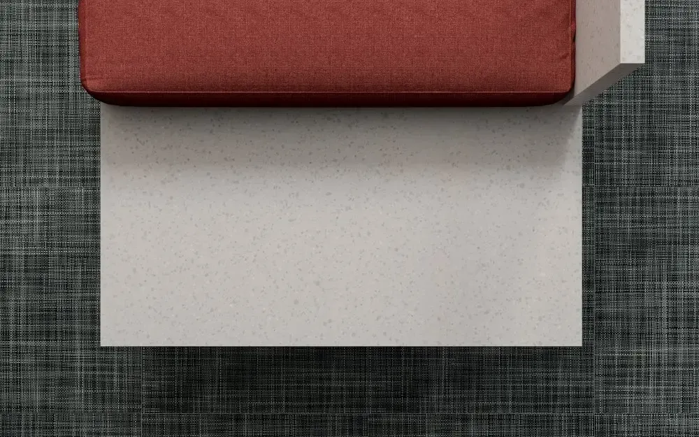 Red cushion on a white block over a gray, textured surface.
