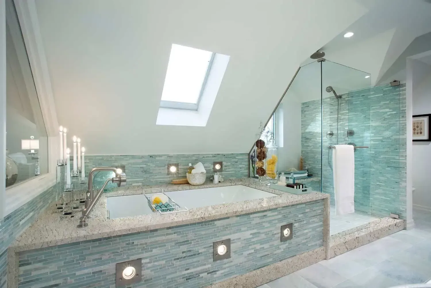 Modern bathroom with skylight, turquoise tiled tub, glass shower, and white walls.