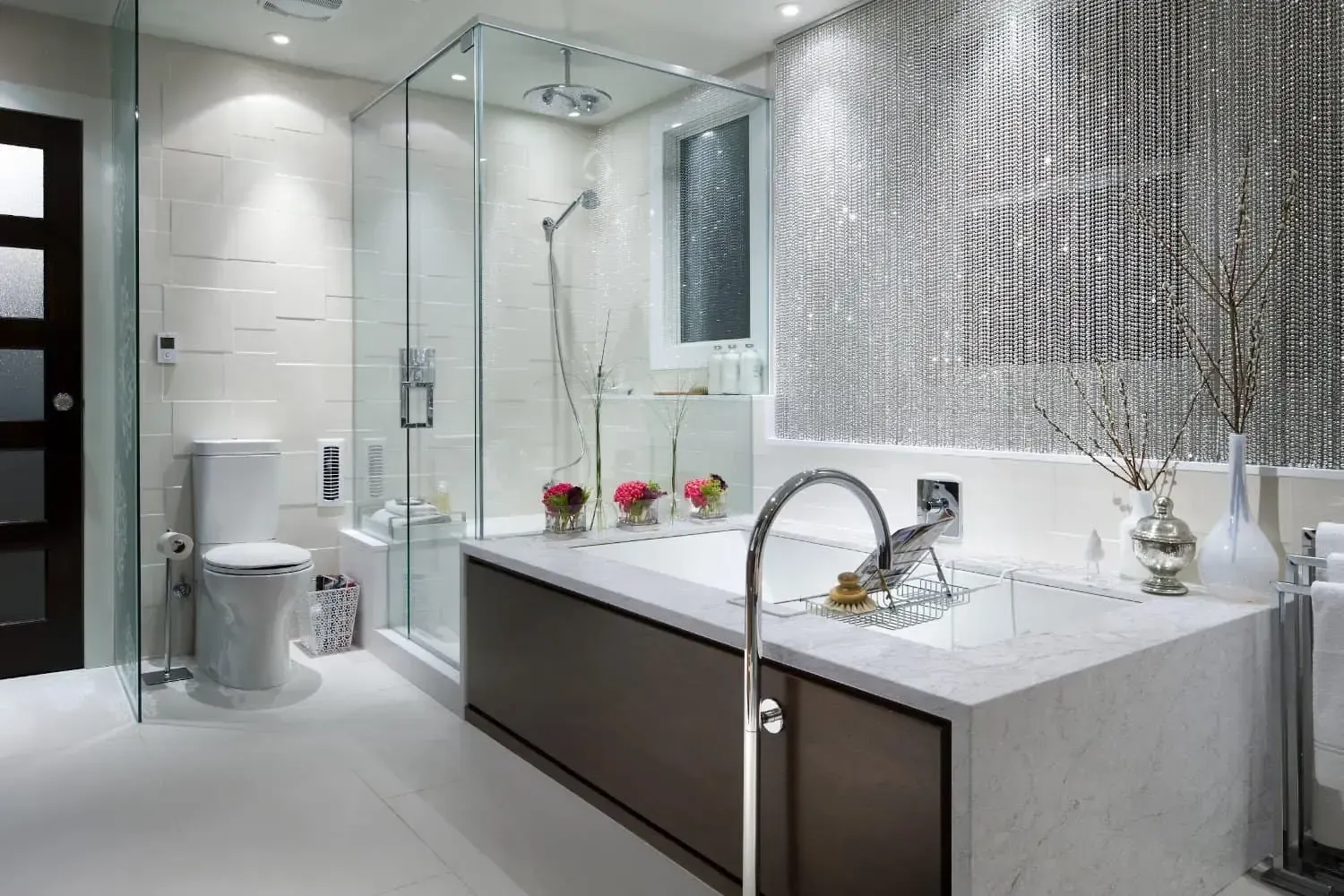 Modern bathroom with a glass-enclosed shower, soaking tub, and decorative wall. Neutral tones, sleek design.