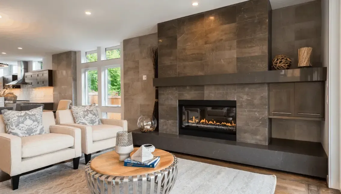 Living room with fireplace, white armchairs, and round coffee table.
