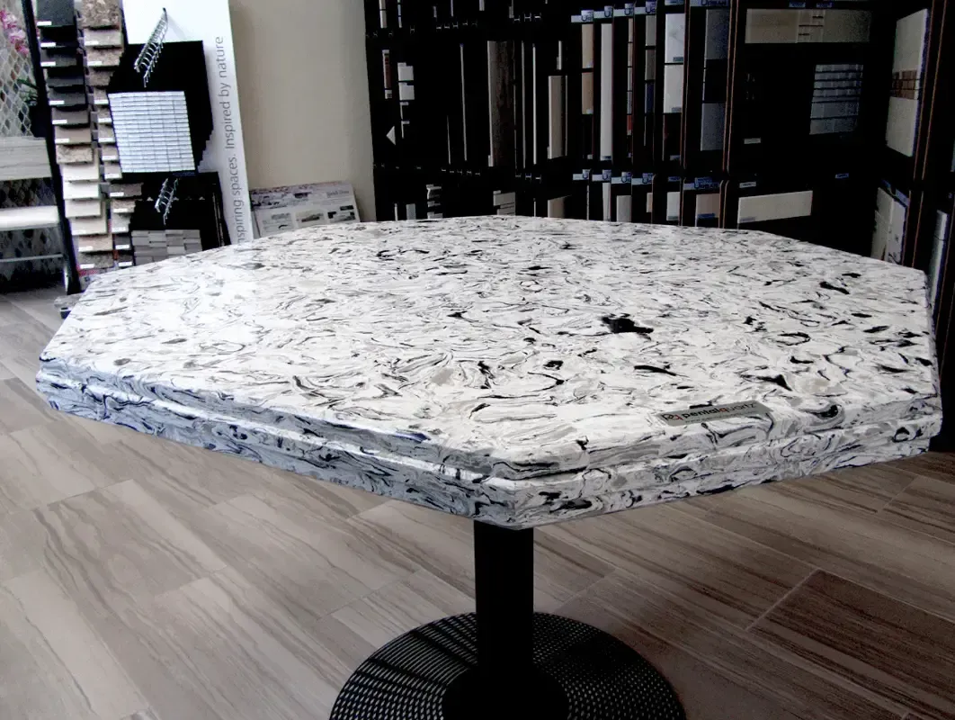 Granite-top table with a black pedestal base, inside a showroom.