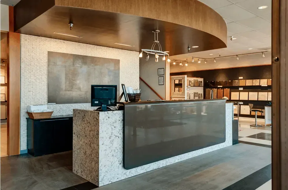 Reception desk in a showroom with gray and speckled accents, brown wood ceiling.