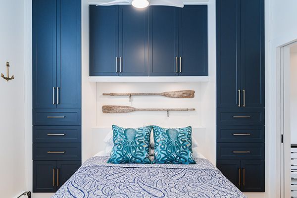 A bedroom with a bed, blue cabinets, and a ceiling fan.