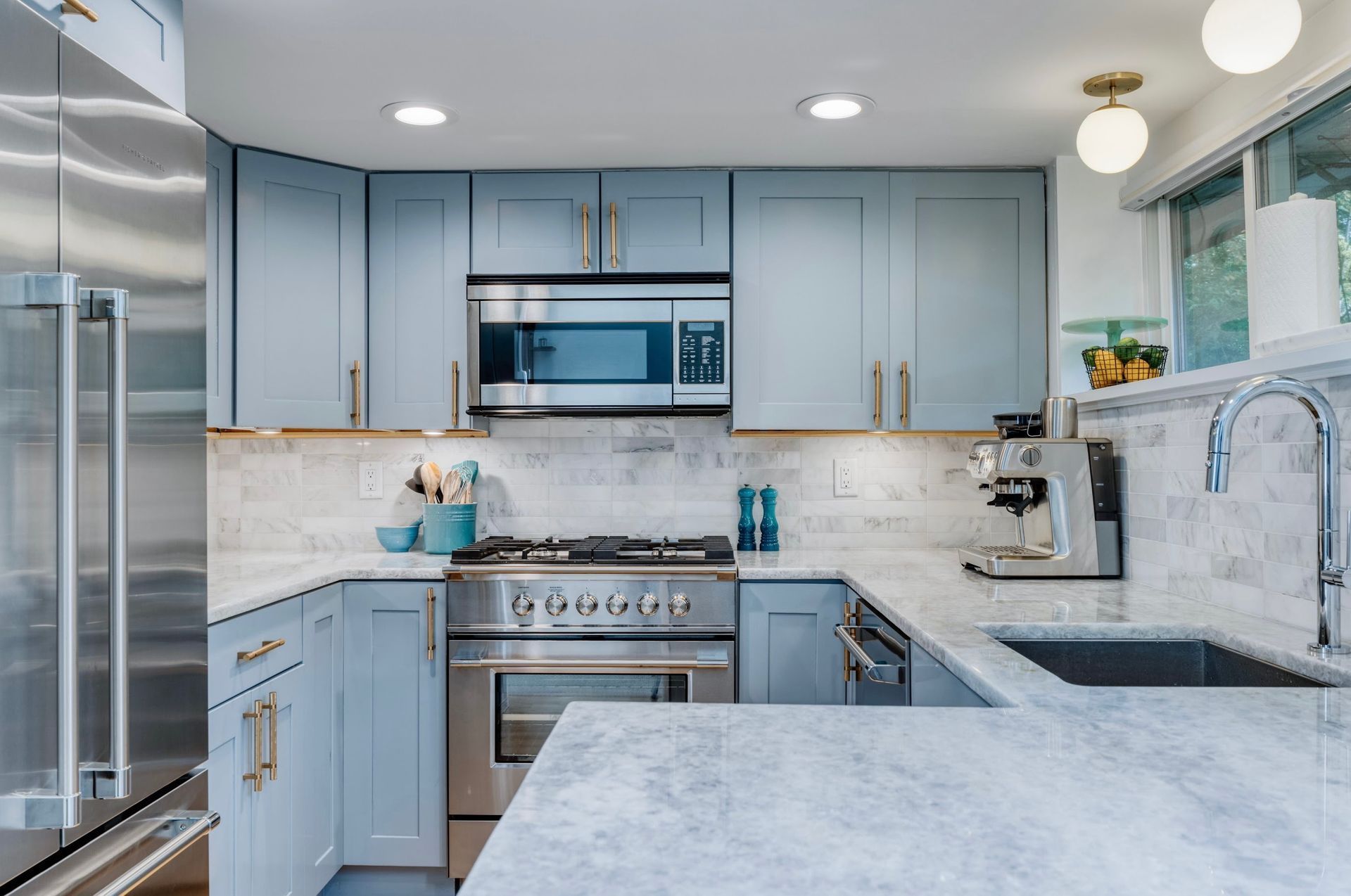 A kitchen with blue cabinets and stainless steel appliances.