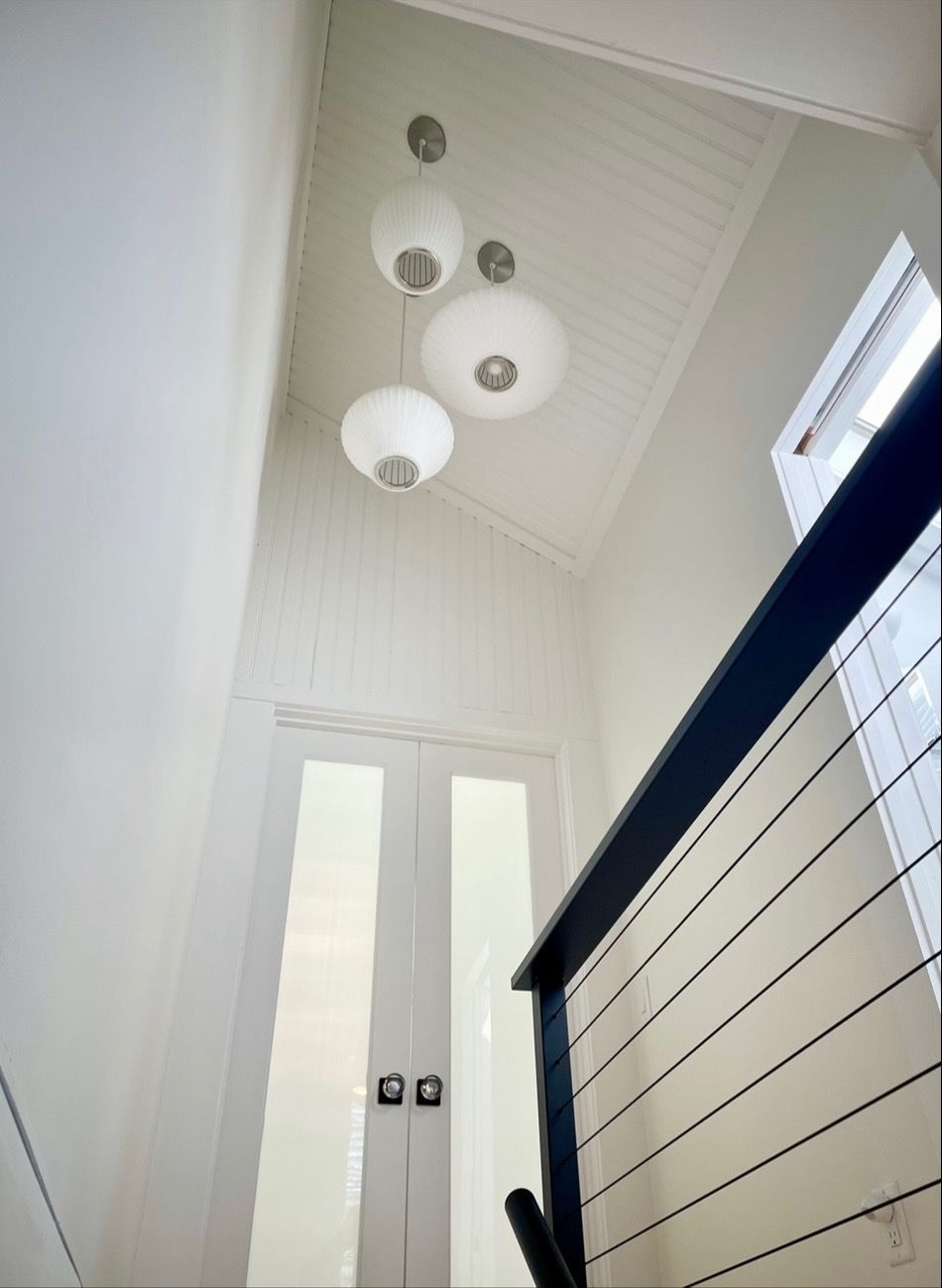 Looking up at a staircase with a ceiling light hanging from it.
