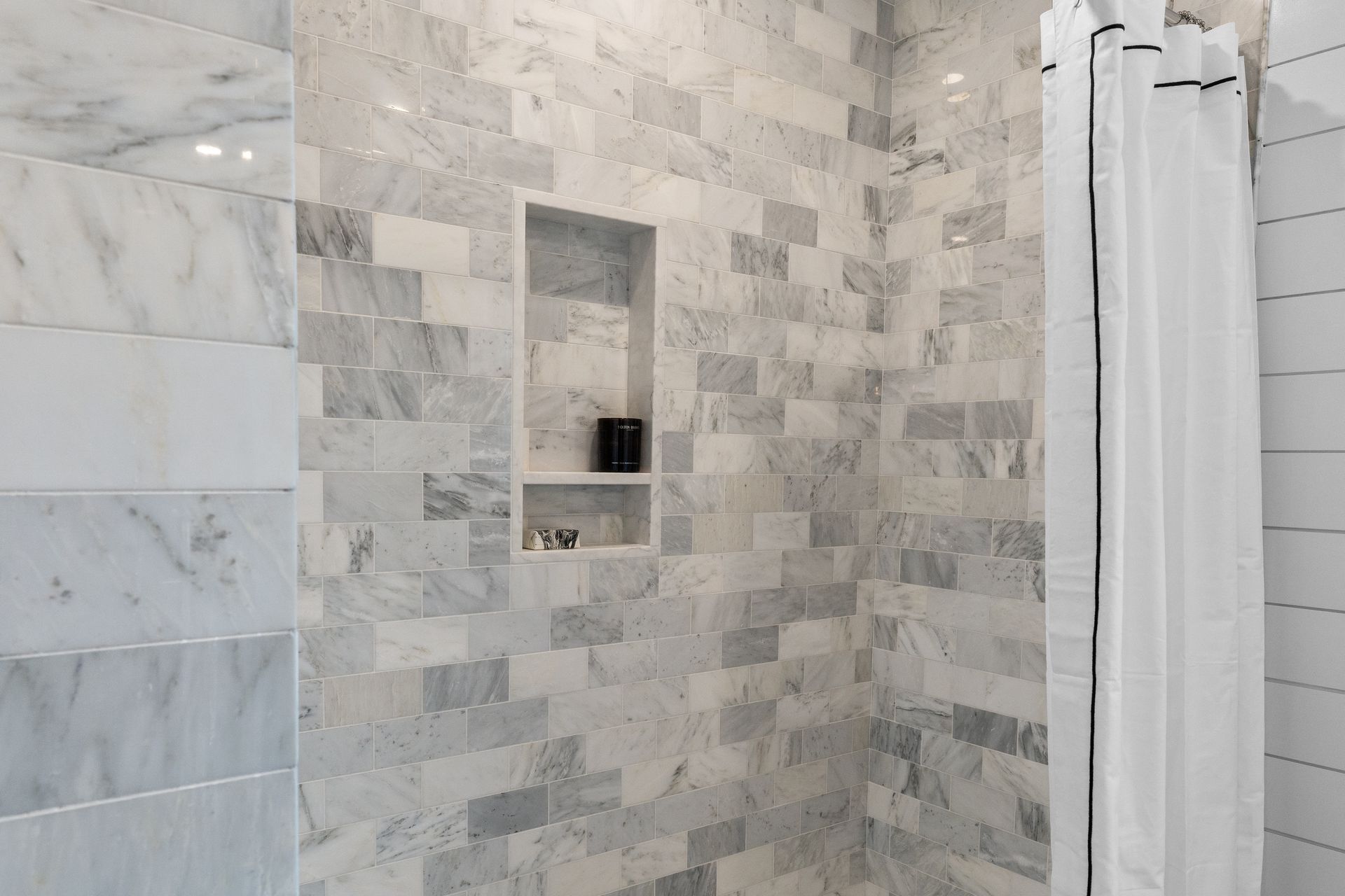 A bathroom with marble tiles and a shower curtain.